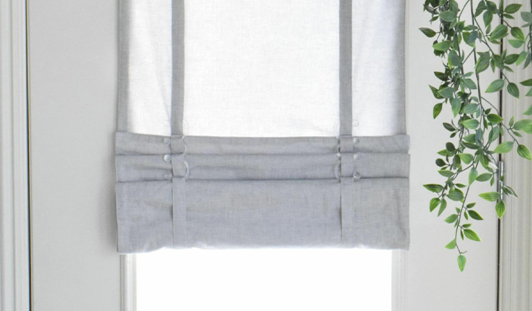 With a tiered tumble shade in Cleveland, you can block sun glare all year round. Gray rolled tumble shade on a glass door